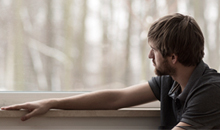 unidentified man with beard looking pensively out a window